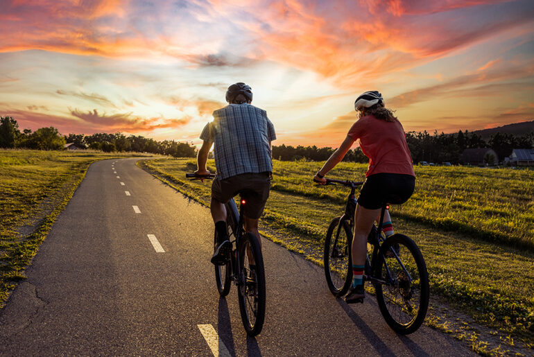 Two people riding bikes along a country road